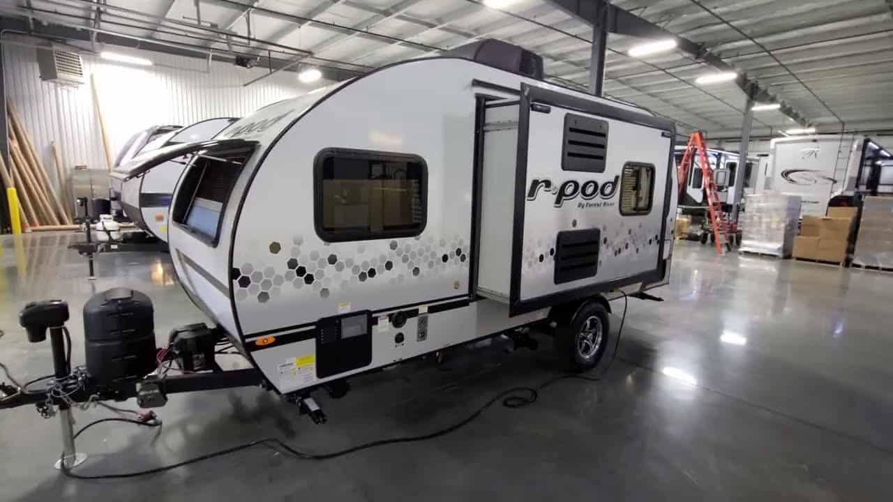 A 2022 Forestriver R-Pod 190, a white and black RV, is parked in a warehouse.