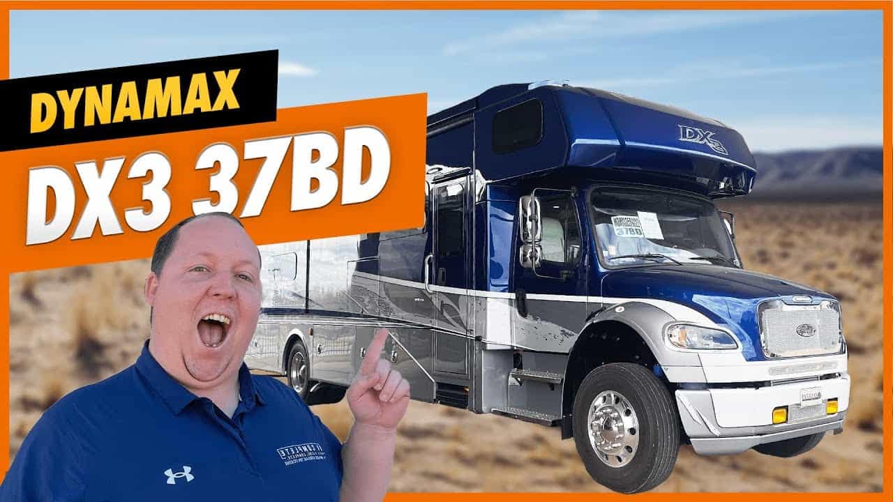A man is standing in front of a Dynamax DX3 RV.
