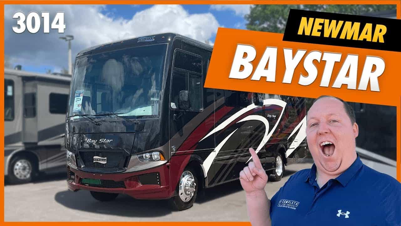 A couple is standing in front of a baystar rv at a State Park.
