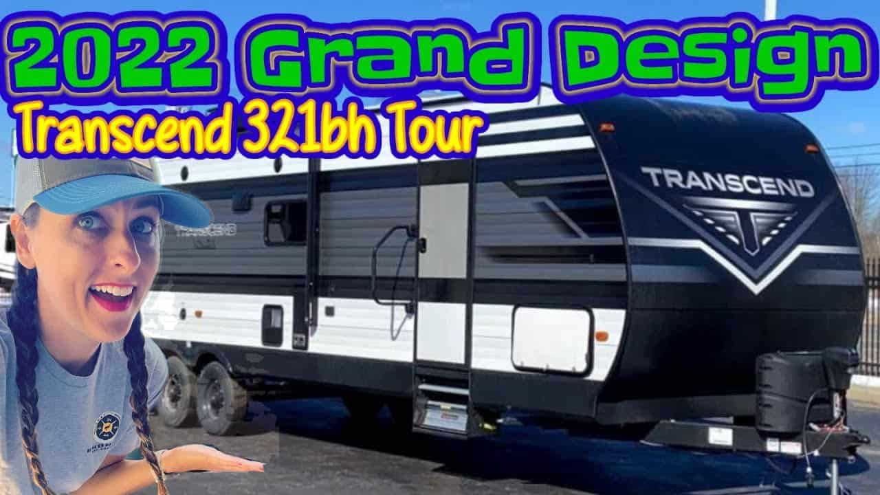 A woman is standing in front of an RV with the words 2022 Grand Design Transcend 321BH, preparing for an exciting RV tour.