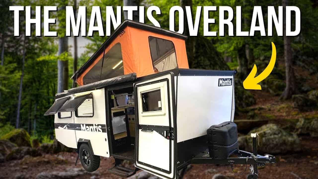 The 2022 TAXA Mantis RV is parked in the woods during a scenic tour.