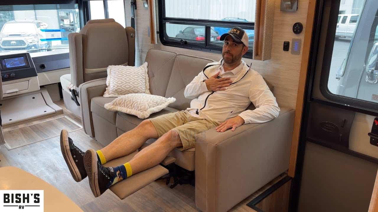 A man comfortably relaxing on a Newmar Canyon Star RV couch while enjoying the scenic tour.