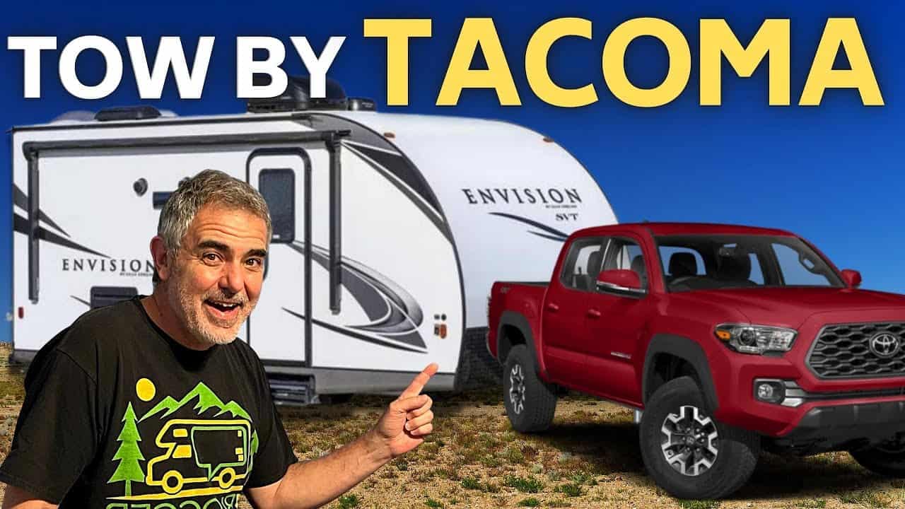 A man is standing next to a Toyota truck towing a towable camper.