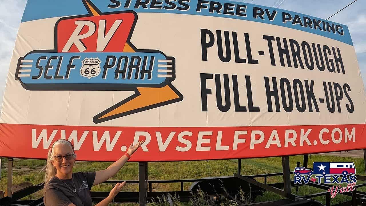 A woman holding a sign advertising an automated RV park with stress-free and full hookups.