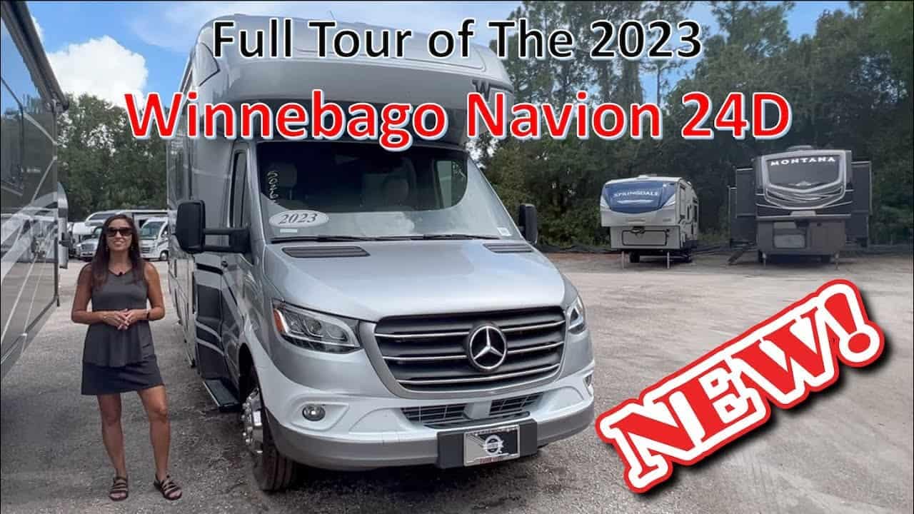 A woman is standing in front of a new Class C RV, the 2023 Winnebago Navion 24D.