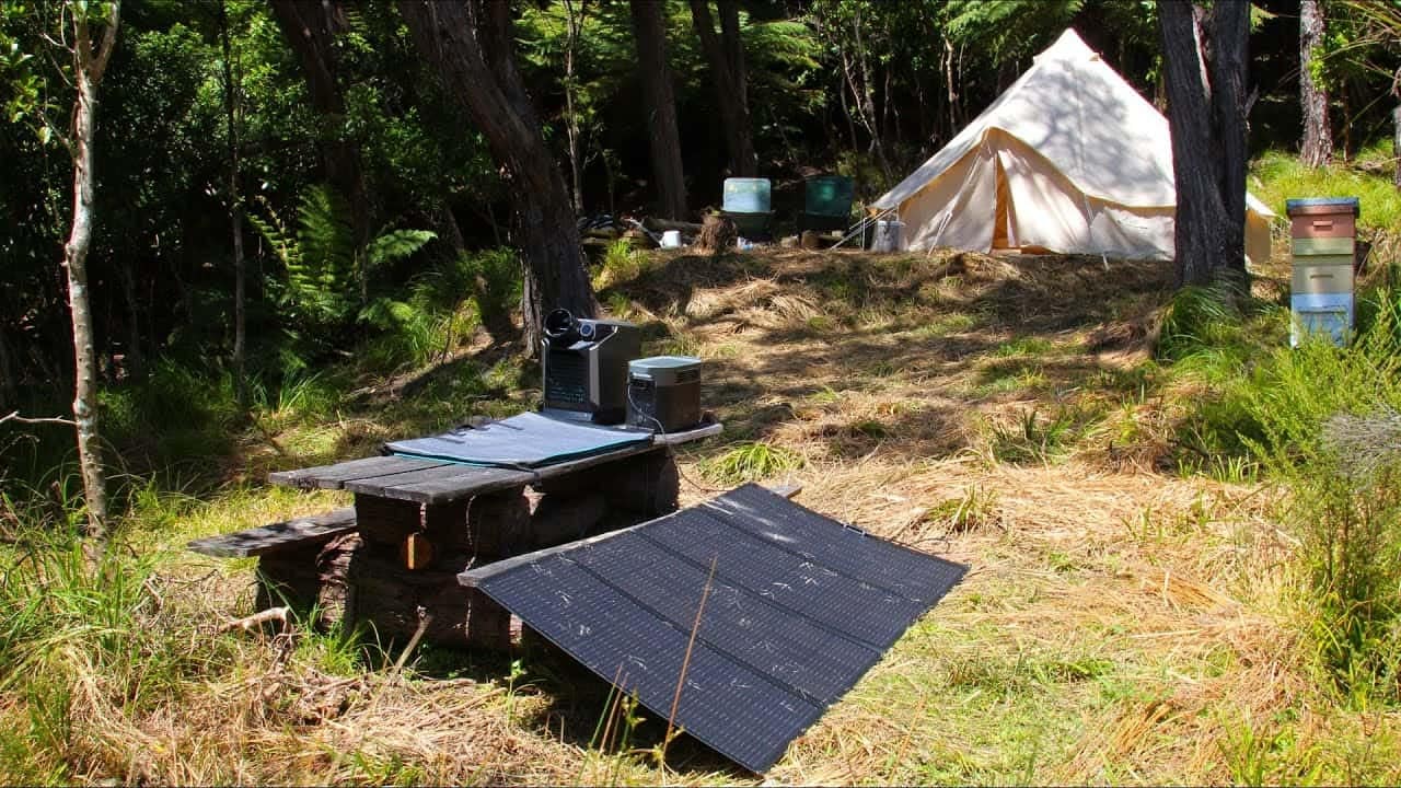 A portable power supply, Delta Max 2000, is set up in the woods with a solar panel.