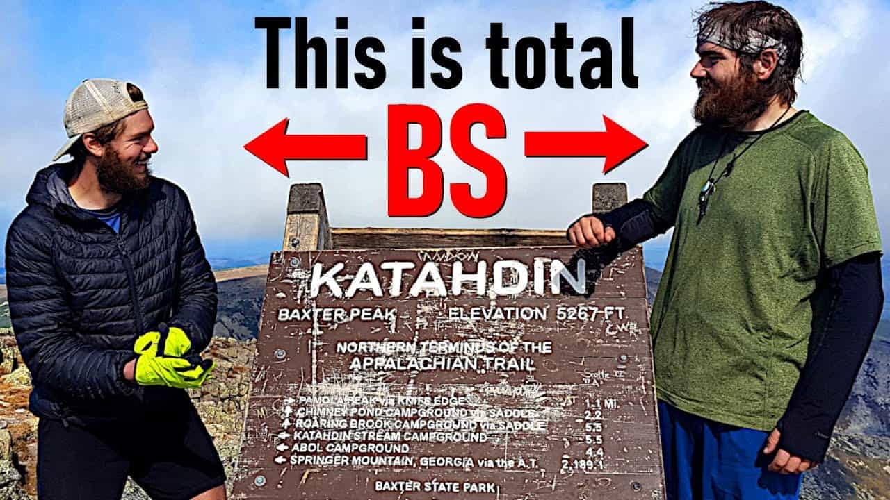 Two men standing next to a sign on their thru hiking journey through nature's beauty, expressing their belief that this is total bs.