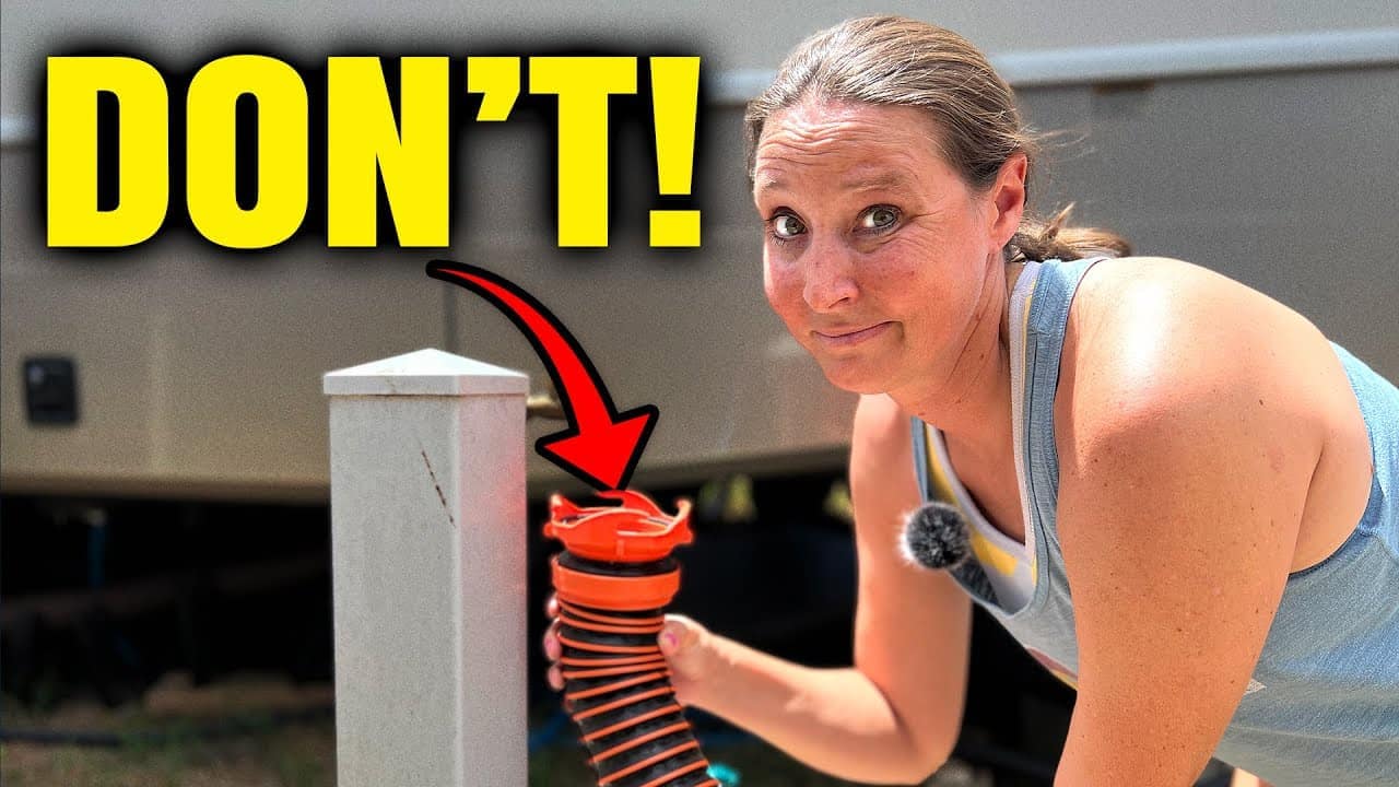 A woman is uncovering an RV at a campsite.
