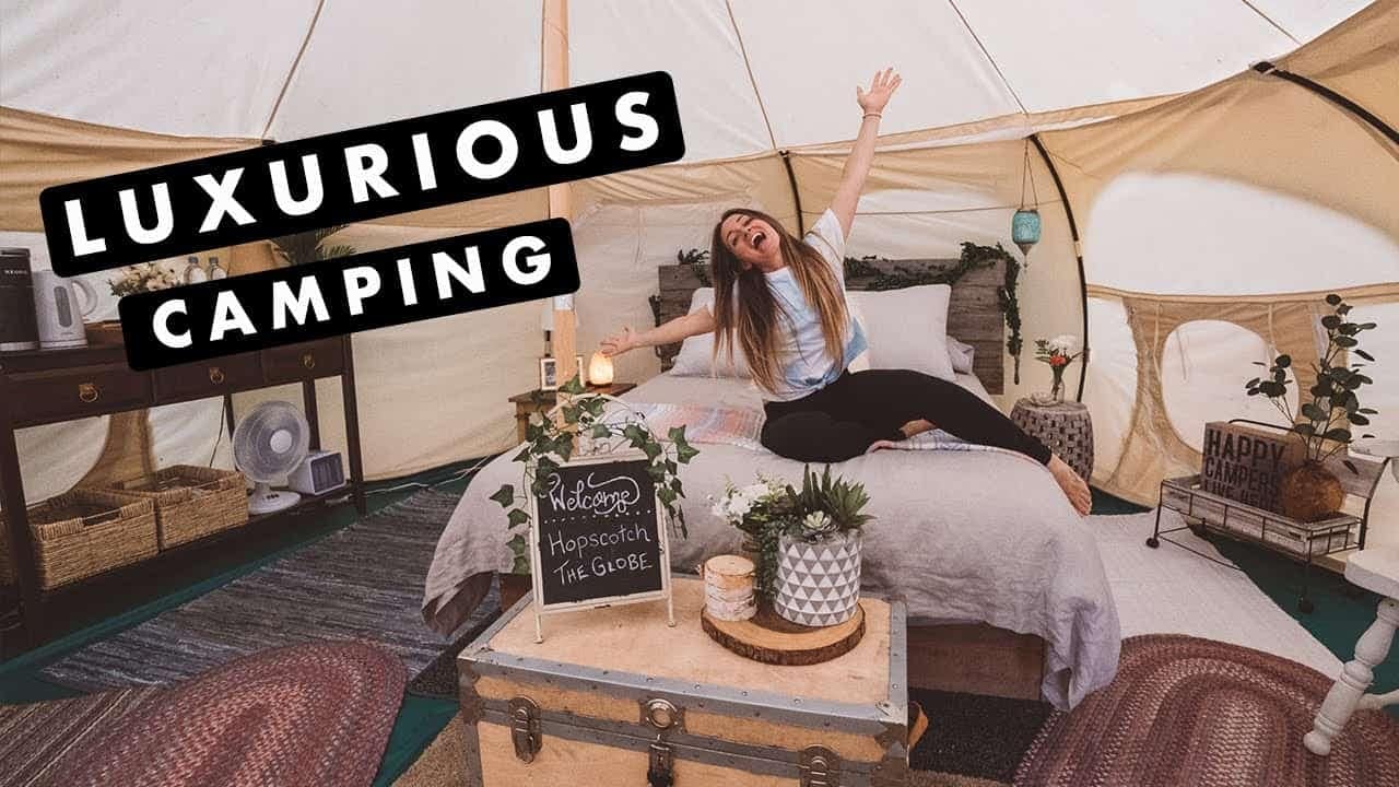 A woman is sitting on a bed in a luxurious camping tent.