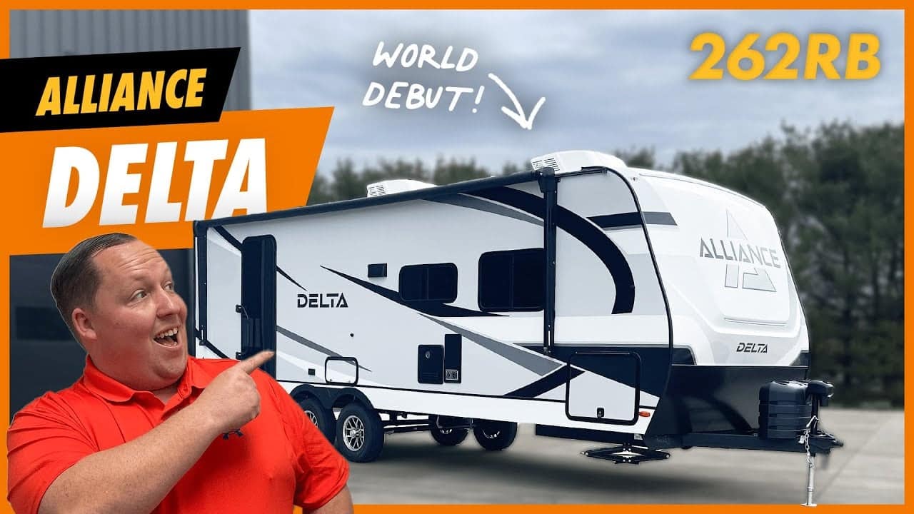 A man is pointing to an alliance delta travel trailer.