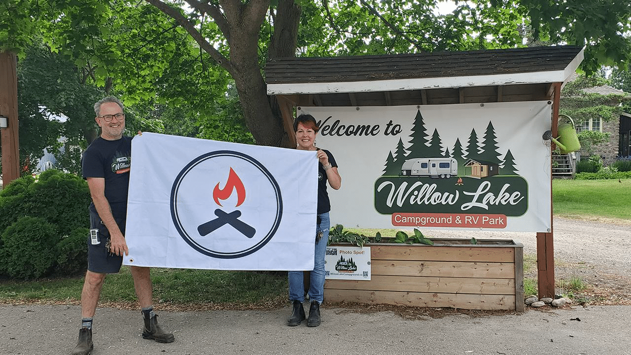 Two people standing in front of a sign that says welcome to Willow Lake, a place known for its diversity and Canadian campgrounds.