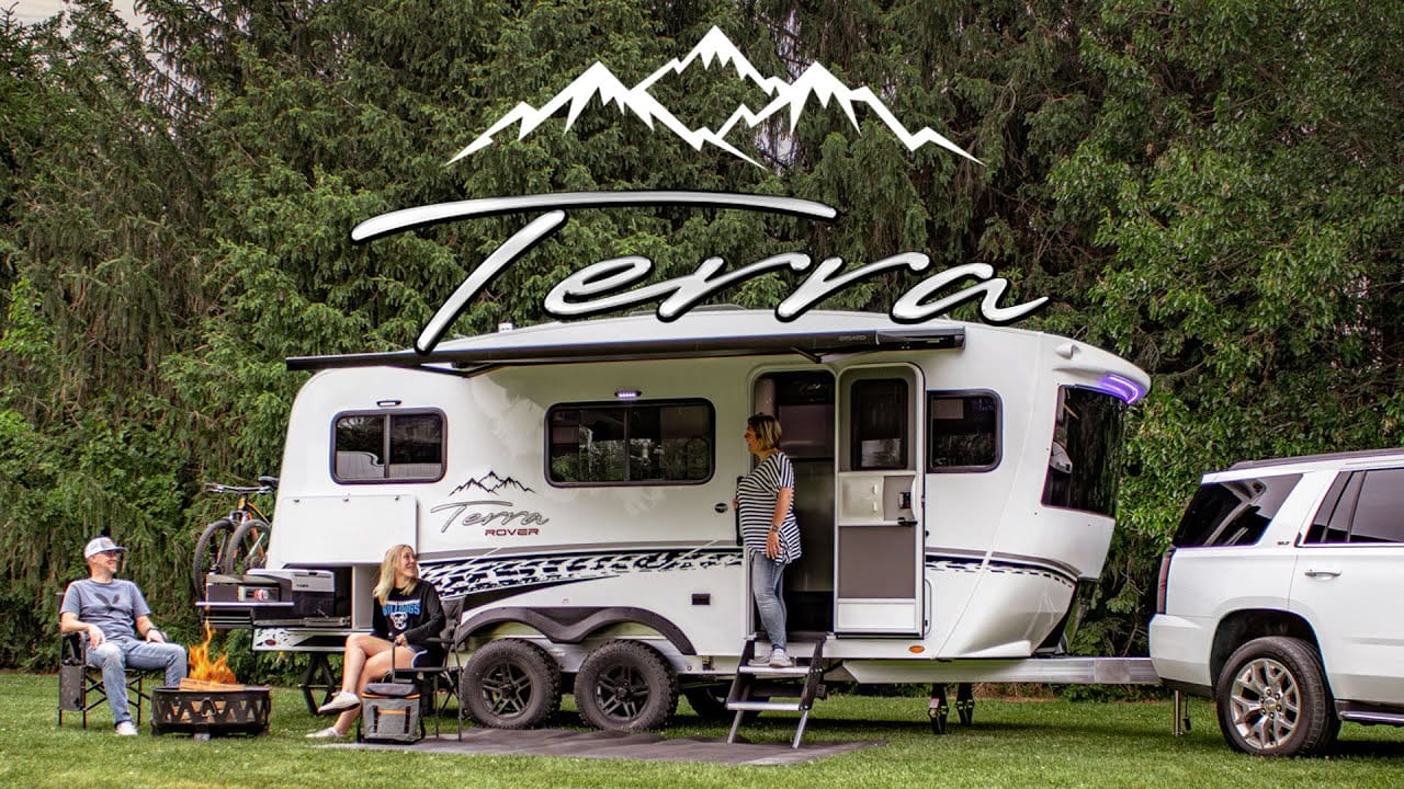 Two people standing next to an inTech RV with the word Terra on it.