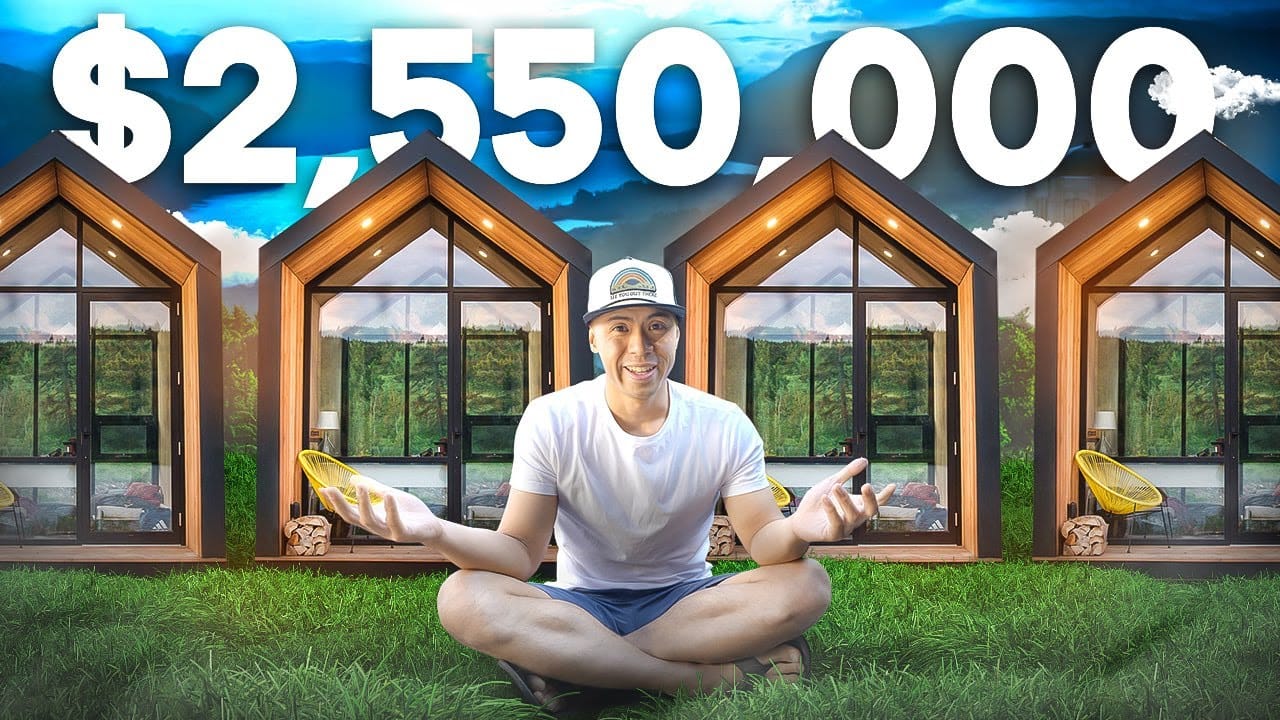 A man is sitting on the ground in front of a unique tiny house.