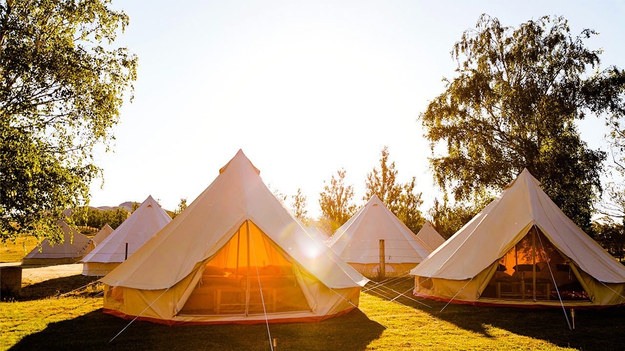 A group of luxury teepee tents on a grassy field, offering a glamping experience inspired by Japan.