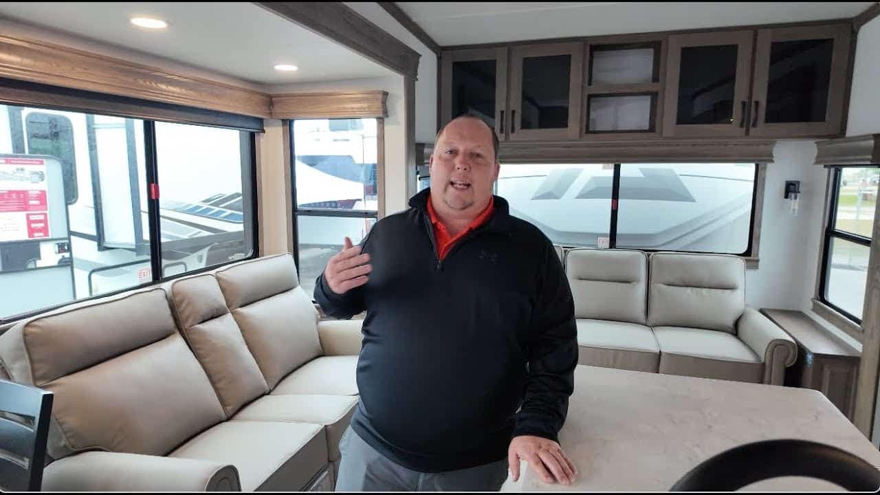 A man is standing in the living room of a 5th Wheel RV.