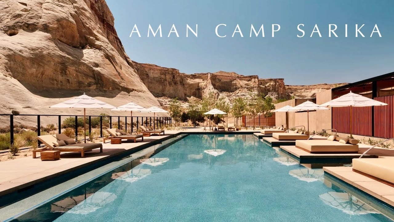 Luxury desert resort pool with lounge chairs and umbrellas at Aman Camp Sarika.