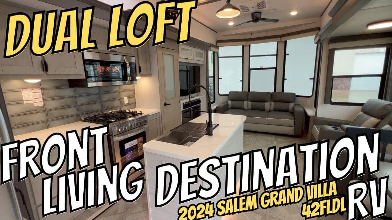 Interior of a modern RV featuring a kitchen with an island, sofa, and dual loft layout with auto draft system.
