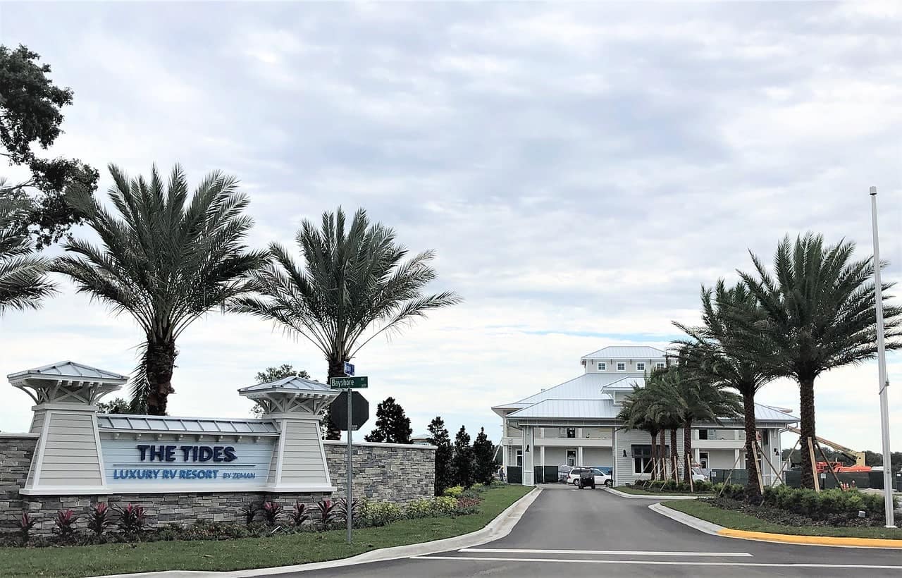 The entrance to Tides Signature RV Resort, a Florida RV Park, adorned with palm trees and a sign.