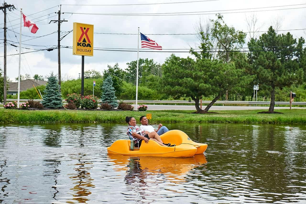 Two people preparing to ride in a yellow boat on a lake at New York campgrounds.