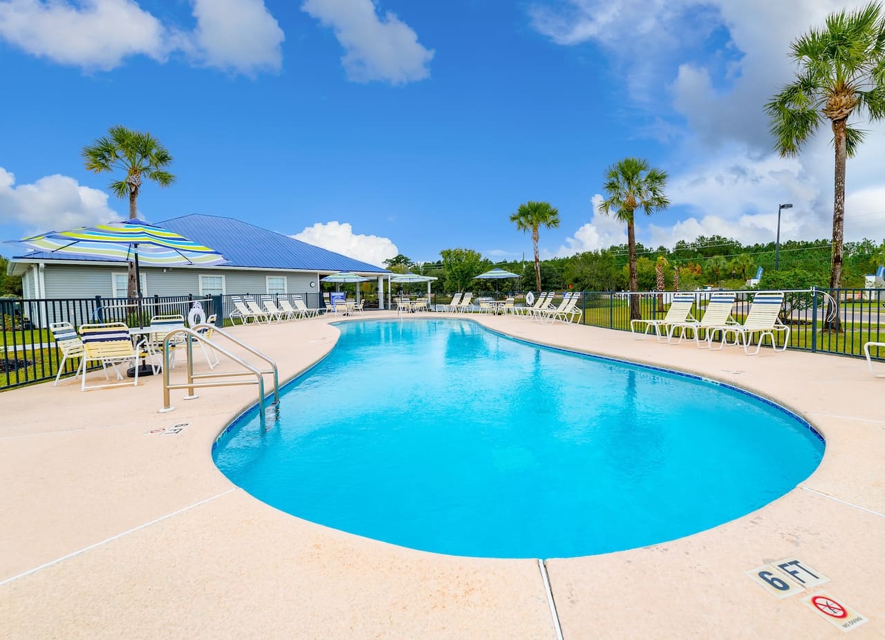 A swimming pool surrounded by chairs and umbrellas, perfect for Snowbirds seeking relaxation at a campground or RV park in Northeast Florida.