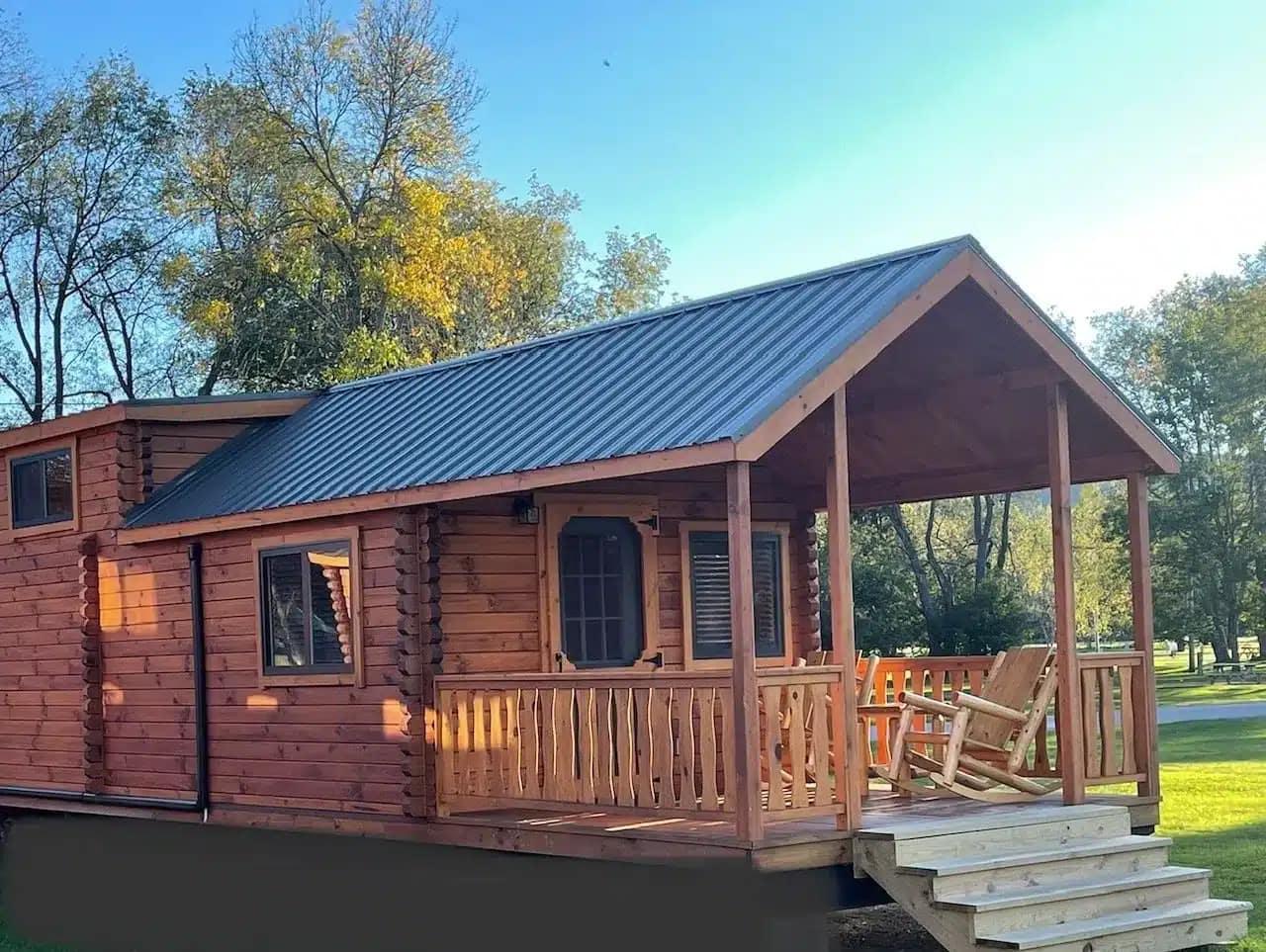 A small log cabin located at Trout Run Camp Resort, sitting on a grassy lot.