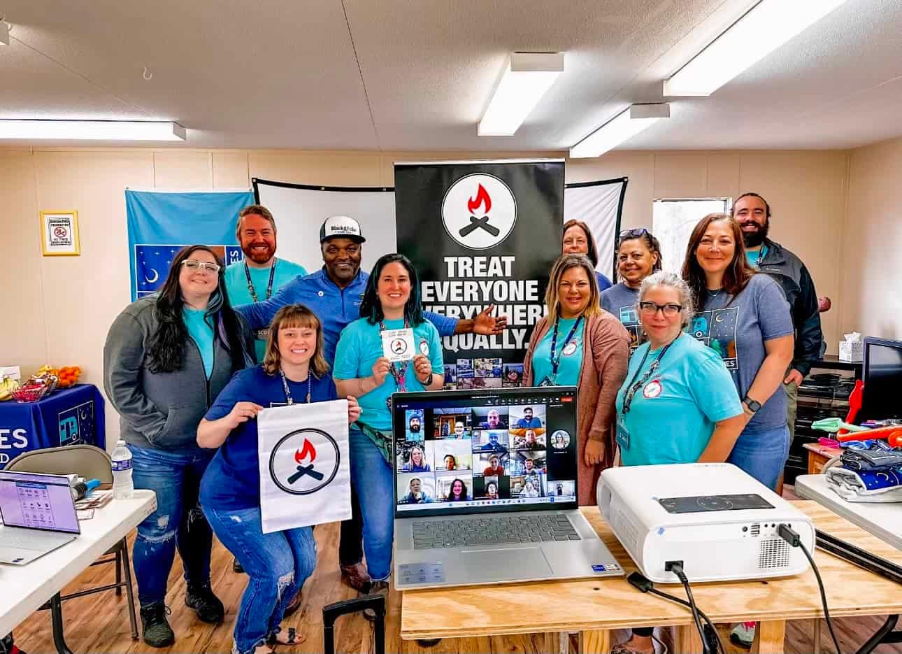 A group of people posing in front of a laptop during a company's Blaze Certification event.