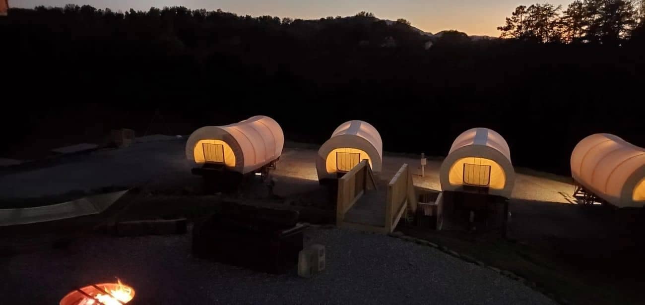 A glamorous campground in Sevierville featuring a cluster of white tents surrounding a cozy fire pit.