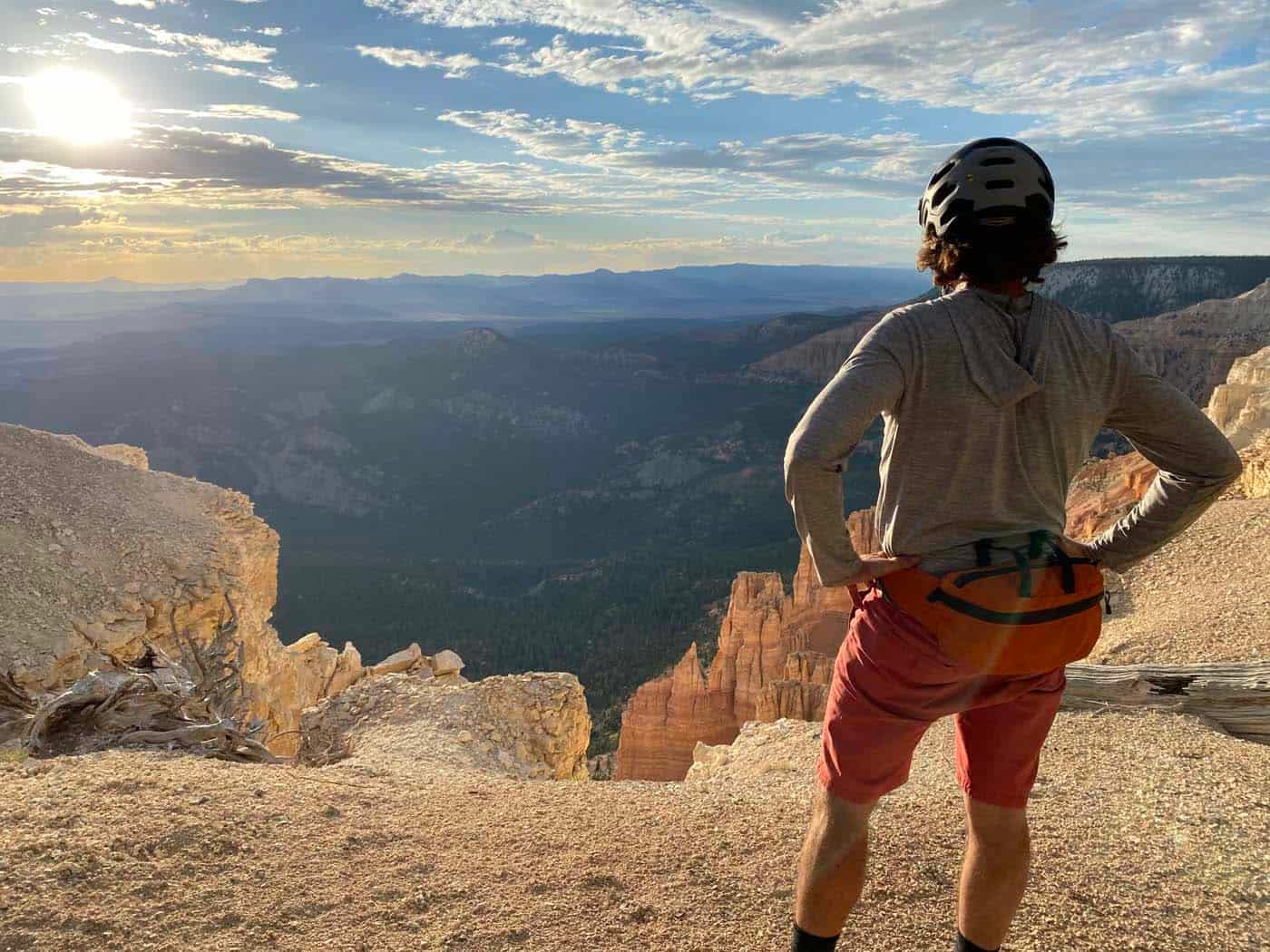 A man standing on top of a cliff in Southern Utah, looking at the sunset.