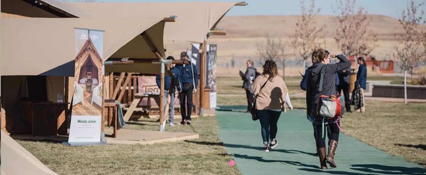 A group of people walking down a grassy area at the Glamping Show USA.