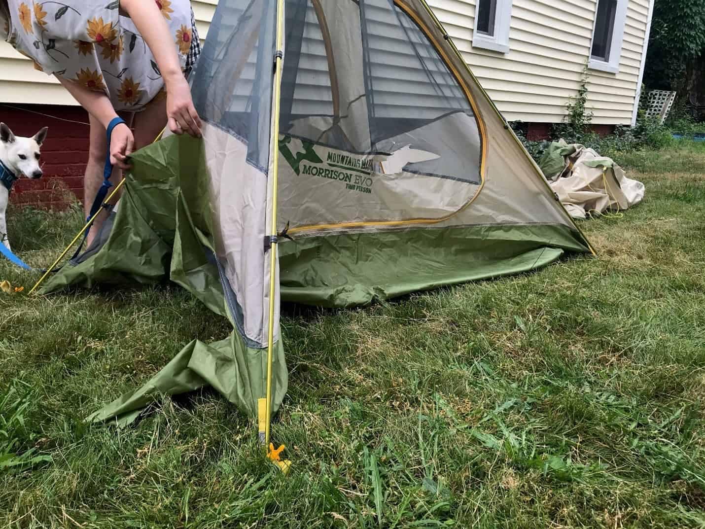 A woman with a dog standing next to a tent at a campground in New Hampshire.