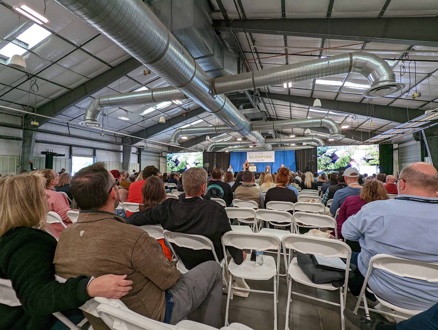 Whitney Scott delivering a keynote presentation to a large group of people sitting in chairs at the Glamping Show USA 2022.