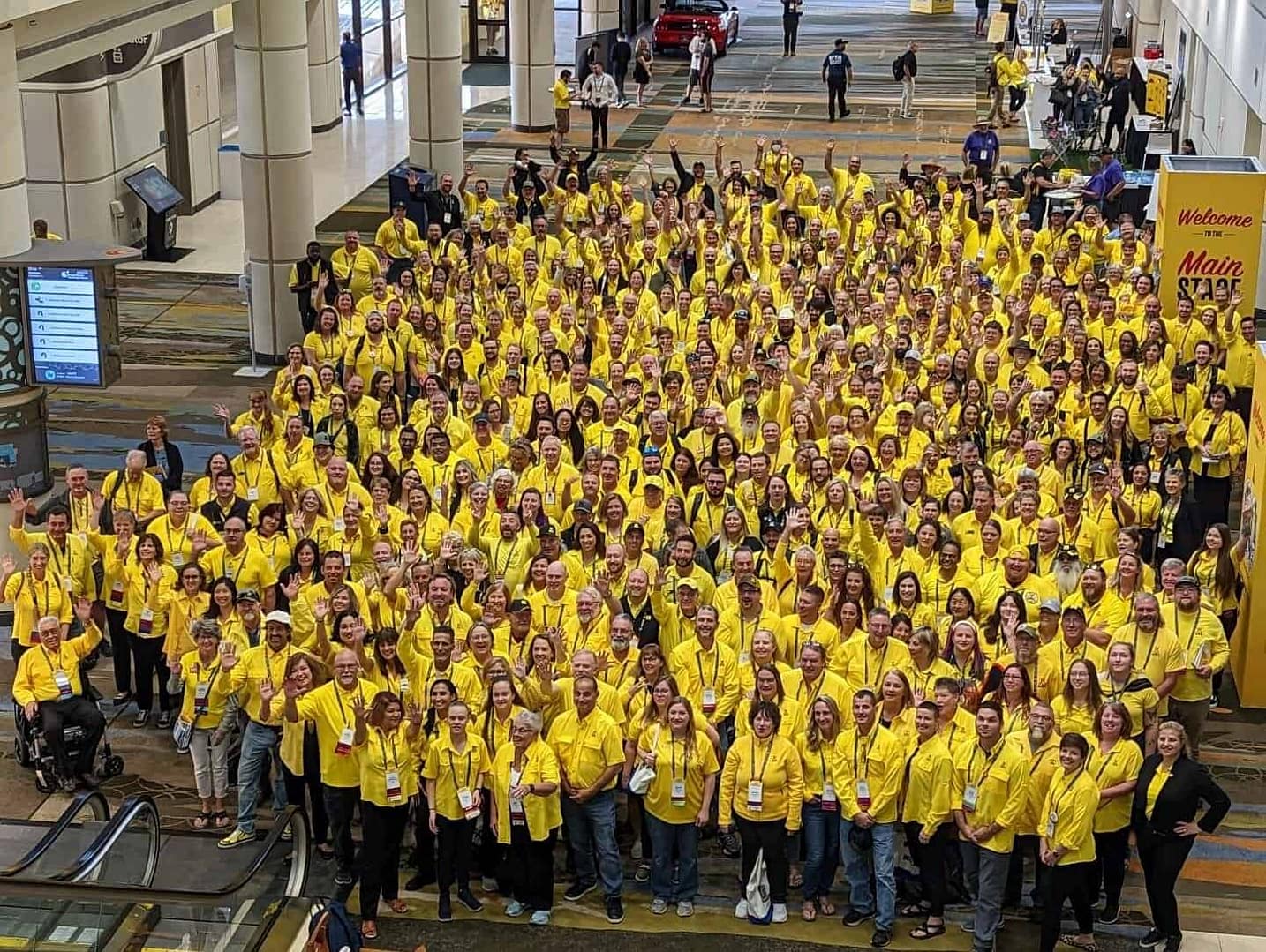 A group of people in yellow shirts posing for a photo at the KOA Expo.