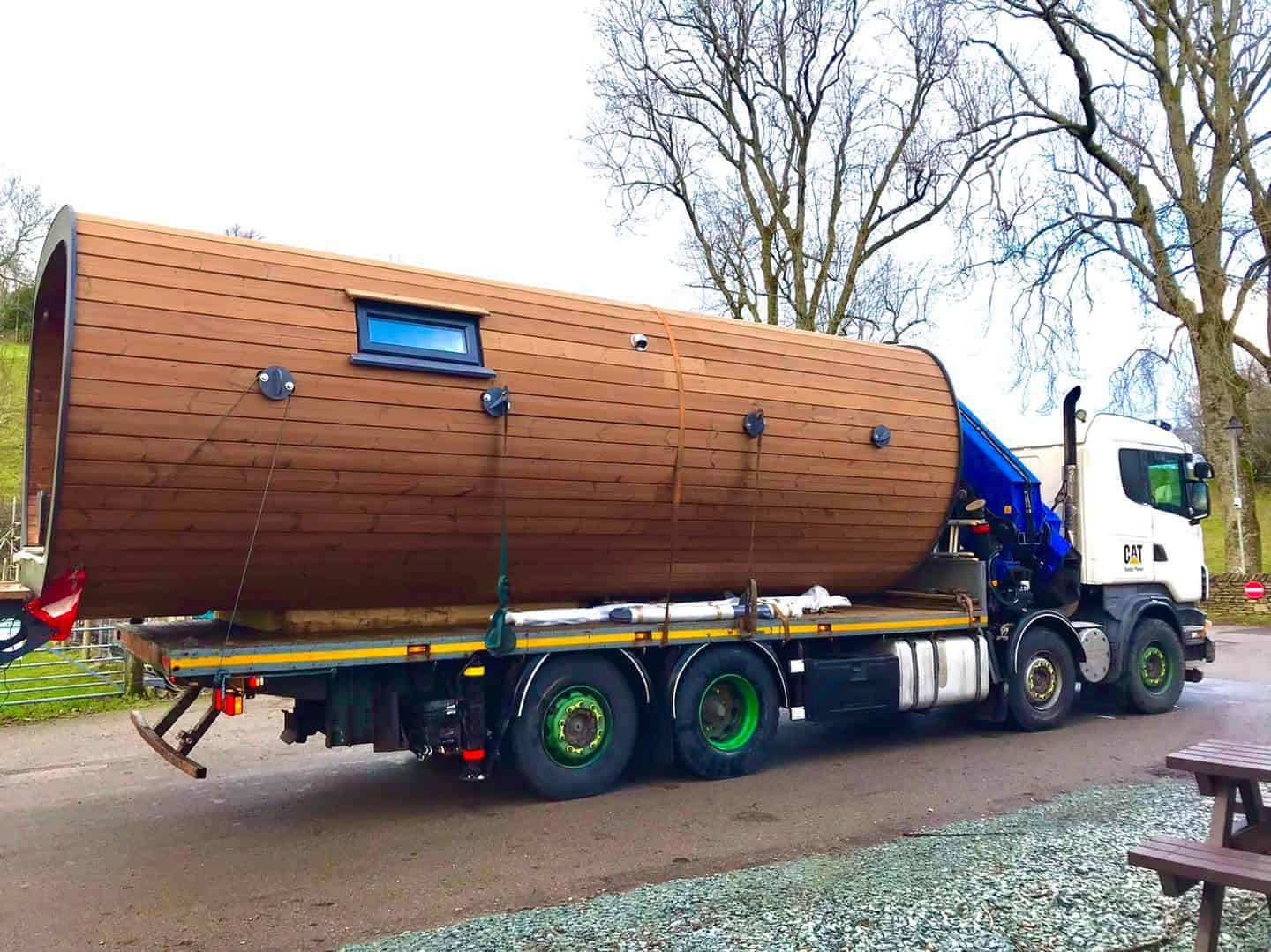 A truck is transporting a large wooden house to the beautiful Lake District for glamping pods.