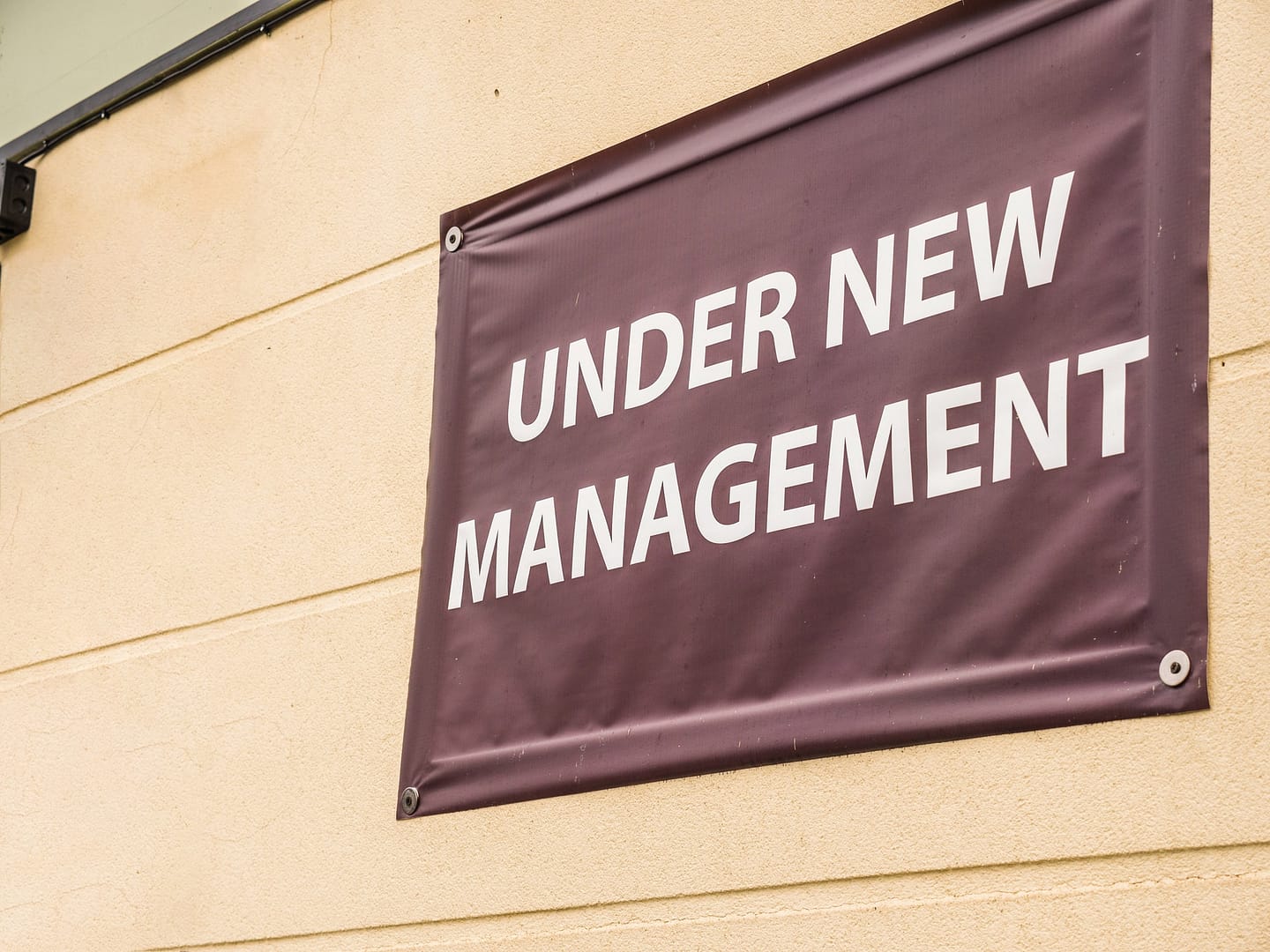 A sign that says under new ownership on the side of a building.