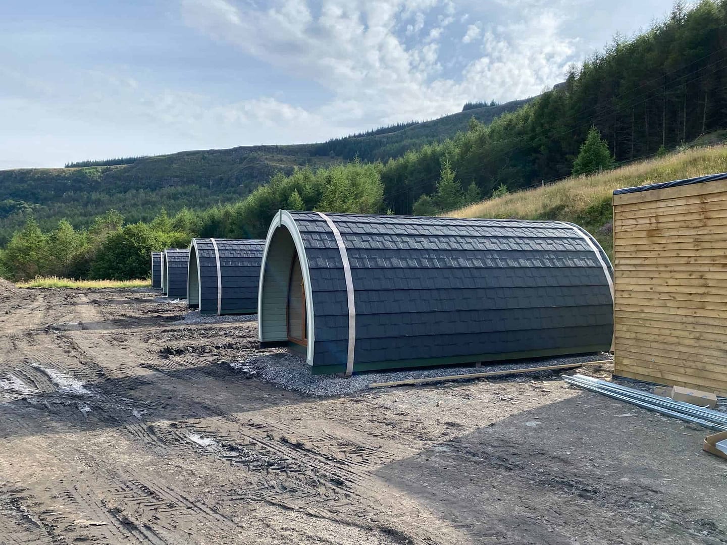 A group of glamping tents on the side of a dirt road, providing a luxurious camping experience for fathers and sons.