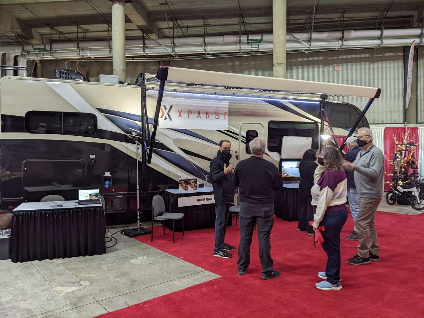 Attendees at the Tacoma RV Show gathered around an RV, showcasing the innovative Xpanse Solar Awning and Xponent Power features.