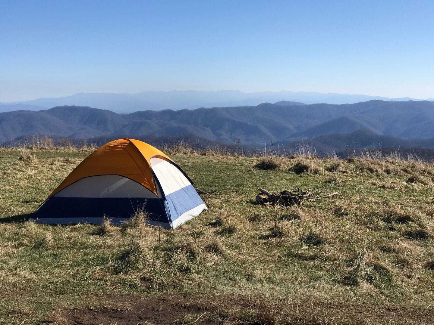 A century-old tent set up on a grassy hill with mountains in the background, hidden gem for year-round campground enthusiasts.
