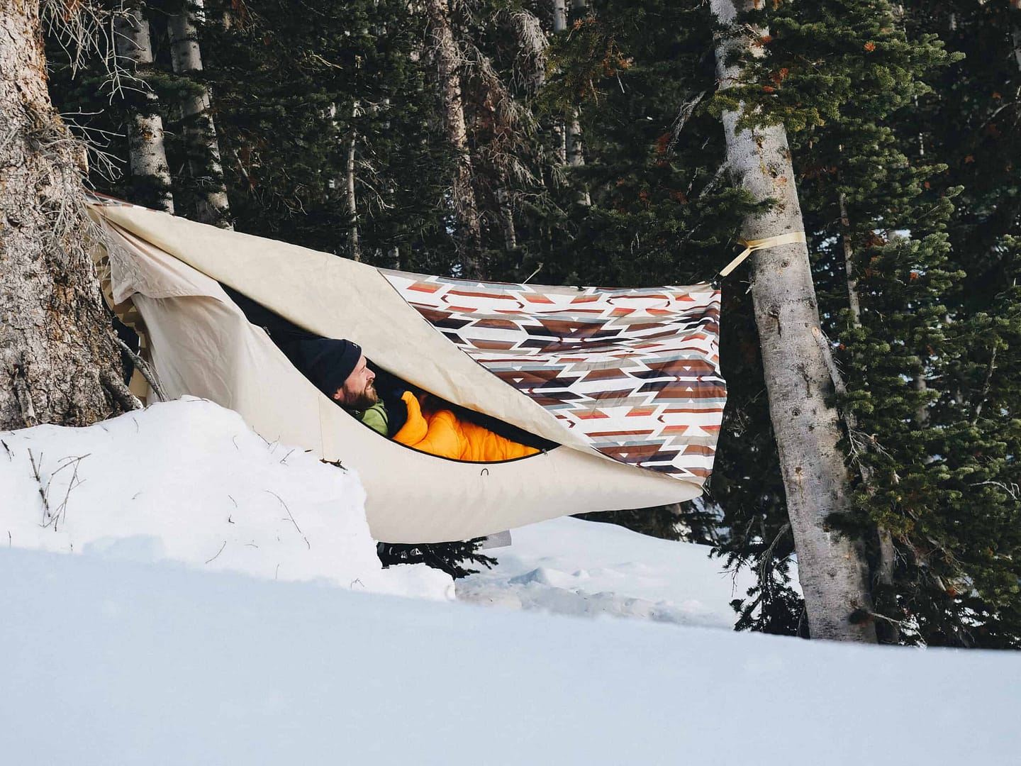 A person peacefully sleeping in a hammock amidst the serene snow-covered landscape, embracing the beauty of nature and experiencing the great outdoors.