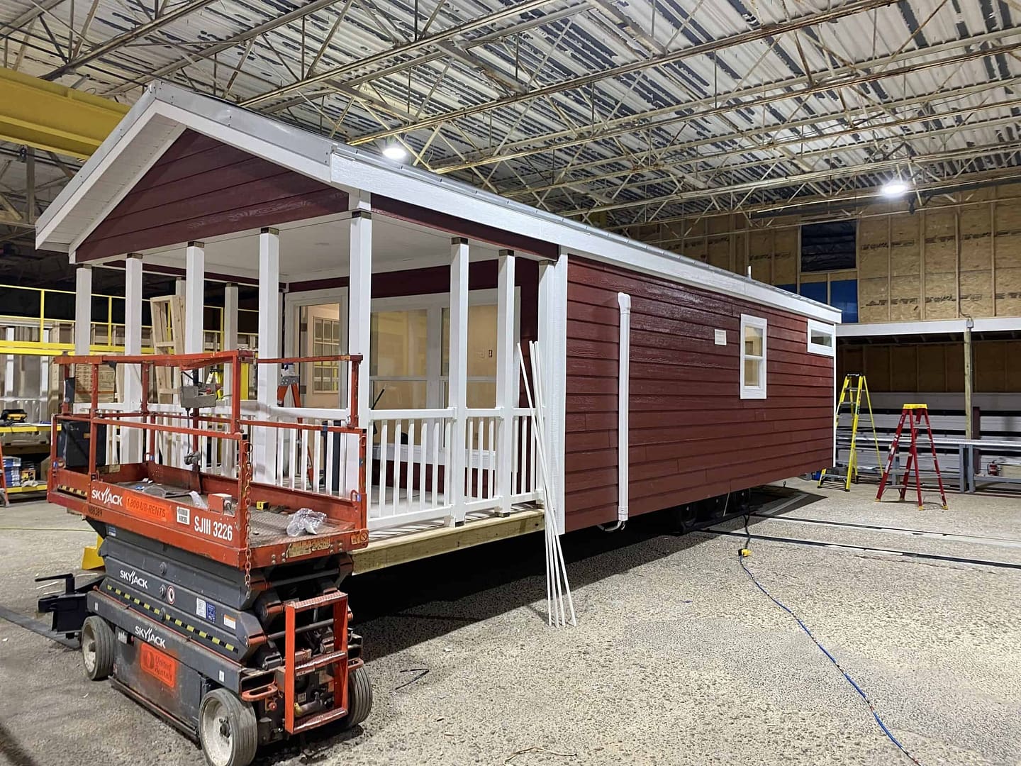 A red and white tiny house is being constructed in a new facility.
