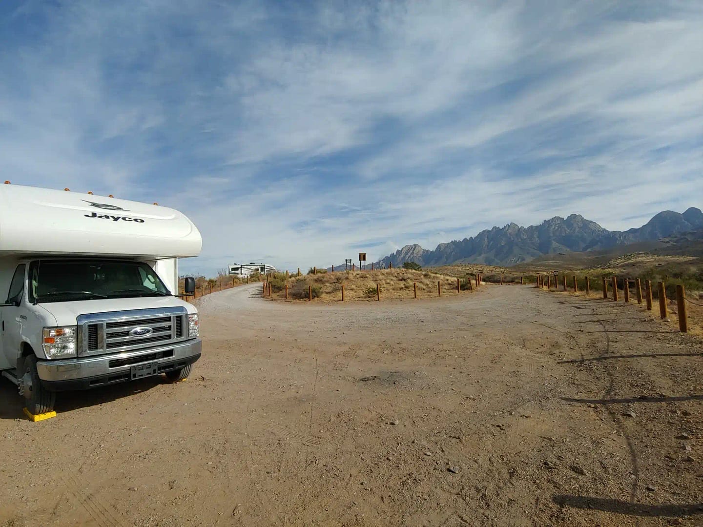 A white rv parked on a dirt road with mountains in the background. The Sierra Vista Campground in the U.S. is considered one of the best places to camp surrounded by scenic mountains and