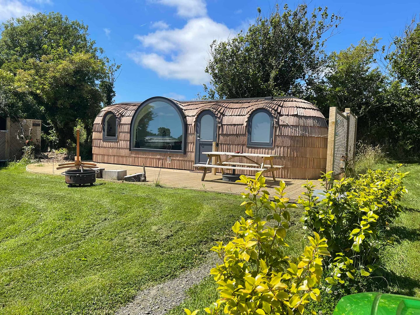 A cozy Lydcott Glamping cabin nestled in the middle of a picturesque grassy field in Cornwall.