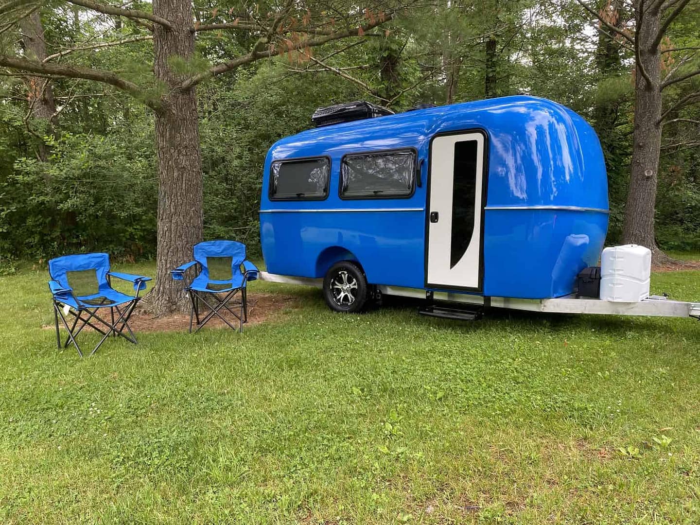 A blue camper trailer manufactured by Cortes Campers parked in a grassy area.
