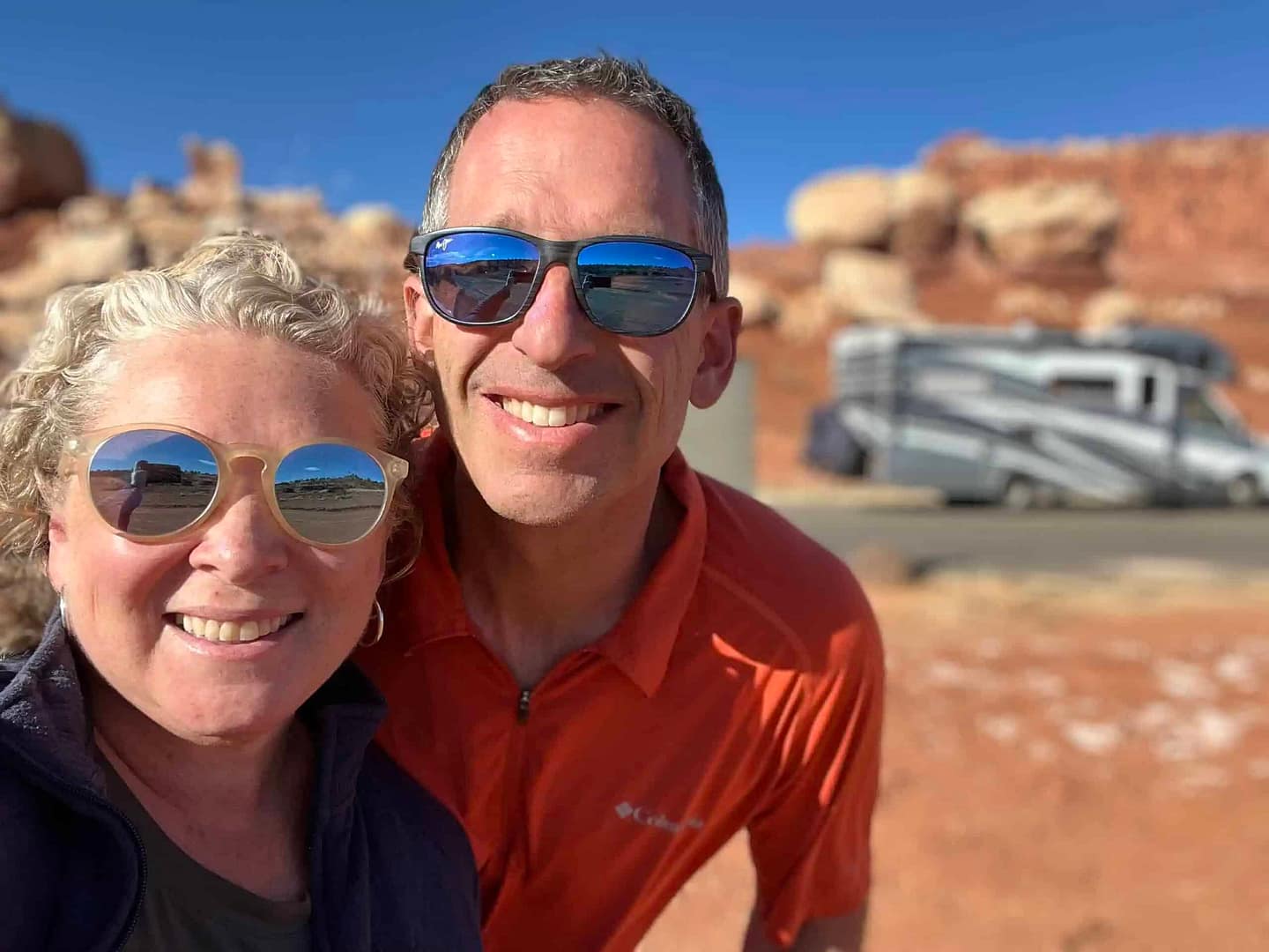 A man and woman RVing in New England taking a selfie in front of their Thousand Trails RV.