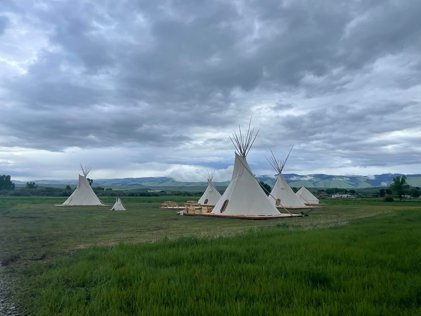 Teepees in a Wind River Basin field under a cloudy sky.