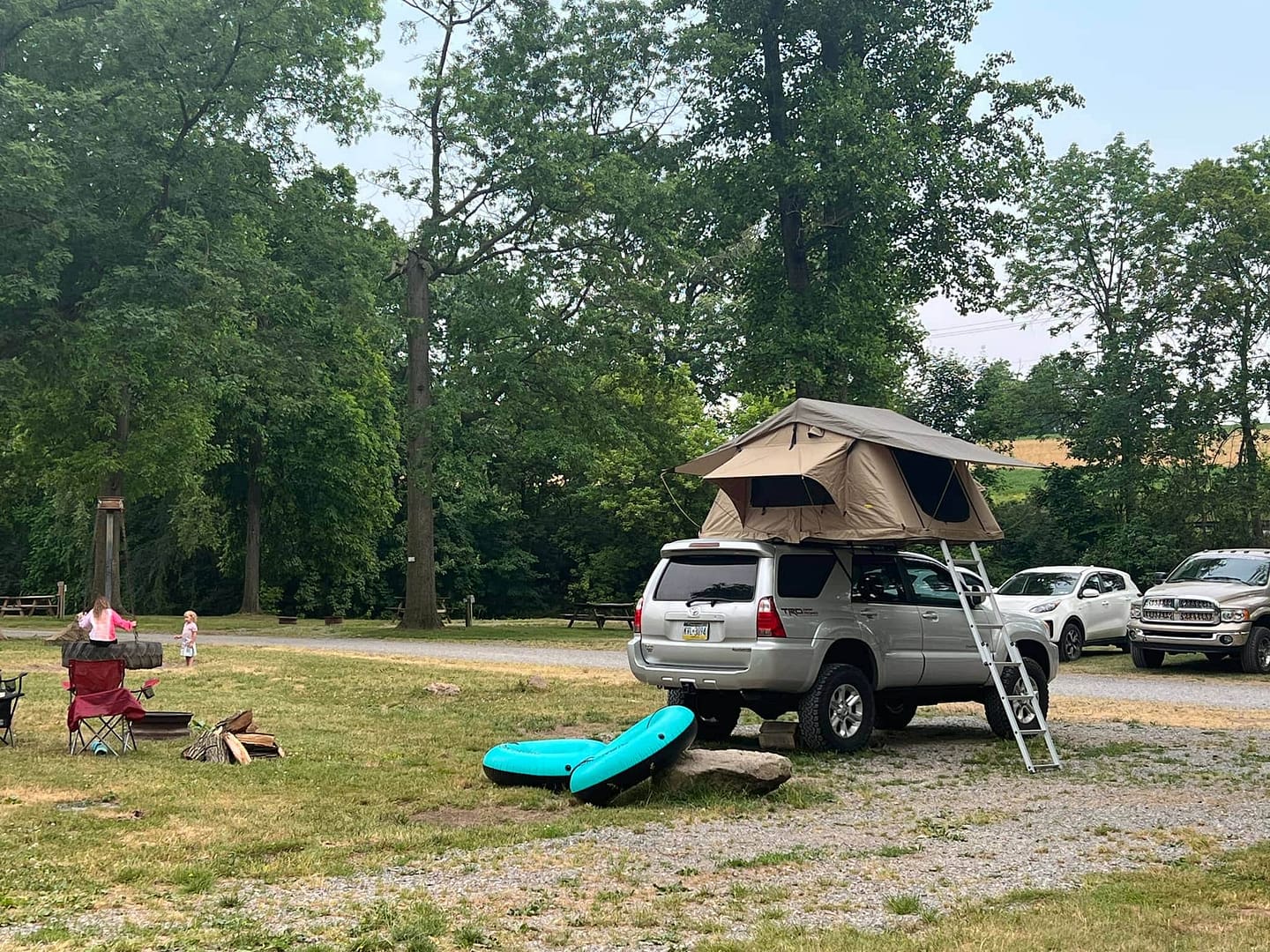 A suv with a tent on top of it parked in a private campground.