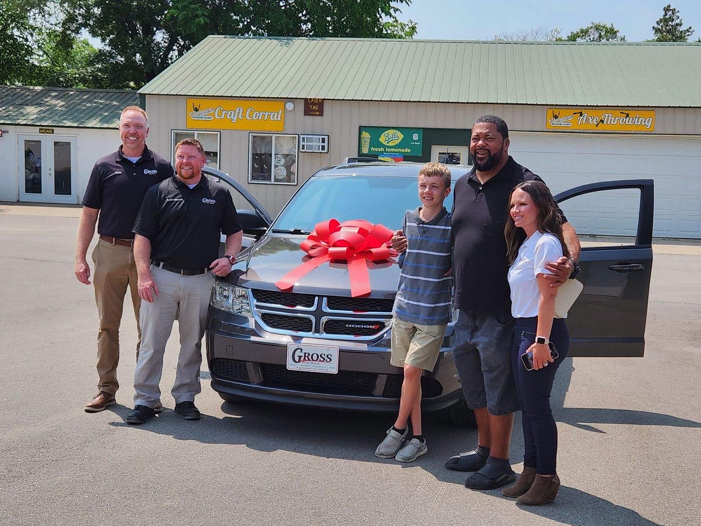 A group of Partners standing next to a car with a bow on it.