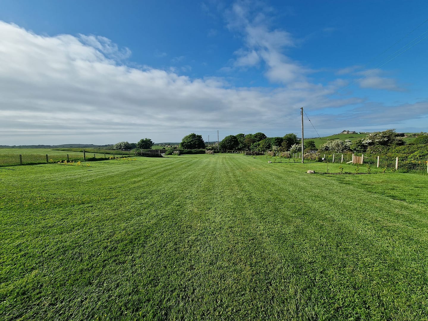 A large field with a lot of grass, part of the Caravan Expansion Plan proposed by Anglesey County Council, featuring space for Glamping Pods.