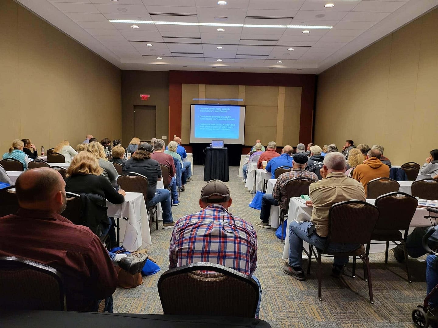 Vendors and park operators gathered at the Campground Owners Expo, sitting in chairs, attentively watching a presentation.