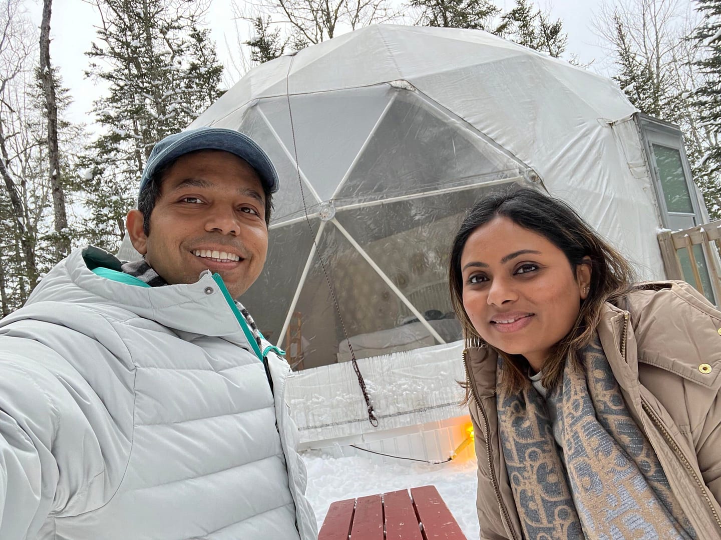 Two people taking a selfie in front of a winter igloo in New Hampshire.