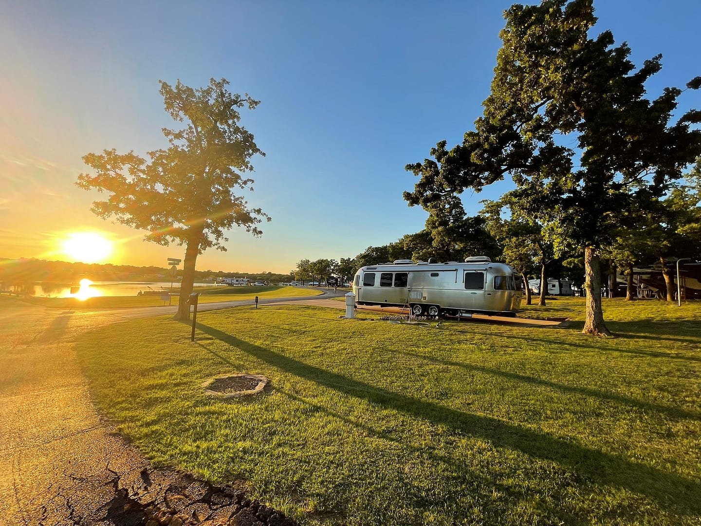 A TACO airstream parked in a grassy area near a lake, perfect for camping in Texas.
